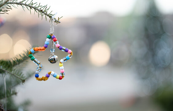 A closeup view of a handmade christmas tree decoration made out of beads and a bell in the shape of a star