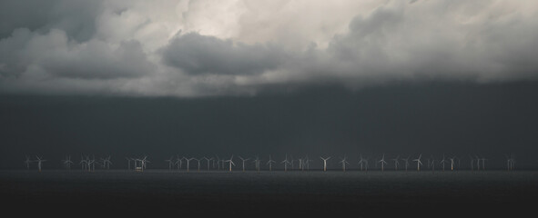 Banner with green energy concept, wind turbine generators. A wind farm in the ocean during a storm