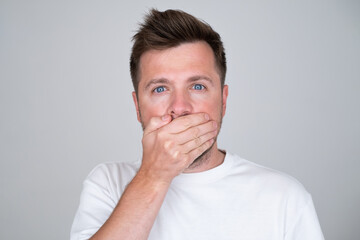 Keeping your secret. man covering mouth with hand and looking at camera. - obrazy, fototapety, plakaty