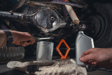 Changing the oil in the front differential of an off-road vehicle, truck with four-wheel drive. Car...
