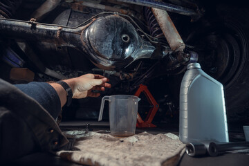 Changing the oil in the front differential of an off-road vehicle, truck with four-wheel drive. Car service. Tools and spare parts. Male hands, mechanic. View from the first person