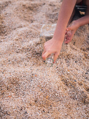 happy girl playing in the sand on the beach with a bottle brought by the sea