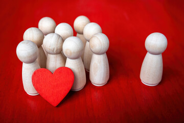 group of wooden figurines holding a red heart and one figure stands by itself