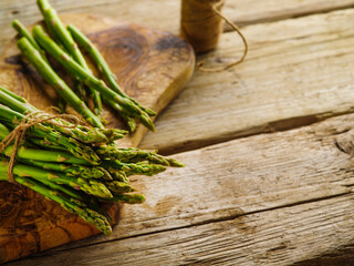 Fresh shoots of asparagus on a cutting board on a wooden background. Useful vitamin product, healthy lifestyle. There are no people in the photo. There is free space to insert.