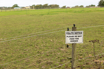 Sign on a farm gate saying Polite notice please do not feed the horses.