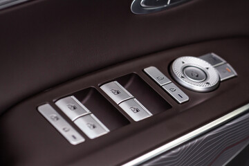 Close up view of button controlling window in modern car interior. Vehicle interior detail. Door...