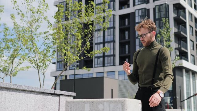 Stop smoking. Serious business man in glasses throws electronic cigarette into a trash outdoors. The young man quit smoking for his good health. A healthy way of life. Man throwing away cigarettes.