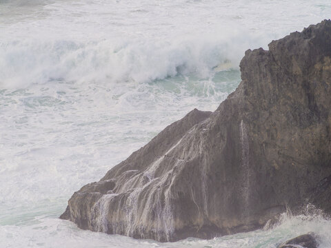 Big rock in the ocean. Raging waves crash against the rock. Storm, element. Beautiful seascape. Monochrome image. Ecology, fresh air, tourism, travel, romance.
