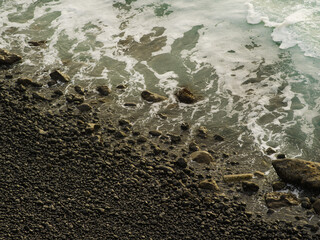 Sea waves crash against the shore. There are many small stones on the shore. Minimalism. Abstraction. Seascape. Ecology. Environmental protection. There are no people in the photo.