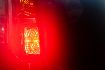 Bright orange car stop lights on blurred red background in dark