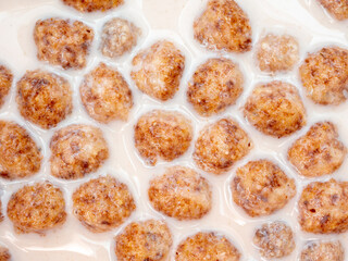 Top view of corn balls floating in milk close up. A quick delicious breakfast of corn flakes and milk.