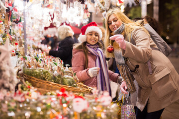 Mother with daughter choosing Christmas decoration at market