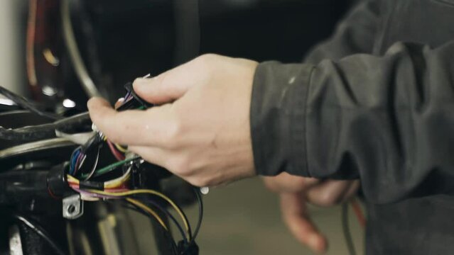 The mechanic sorts out chips for connecting electrical equipment in a motorcycle. Close-up. Transport concept