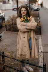 Portrait of cute casual brunette girl in glasses melling a bouquet of yellow tulips. Photo of cute sweet lady girl hold tulips bunch present she get on 8-march 14-february from her boyfriend