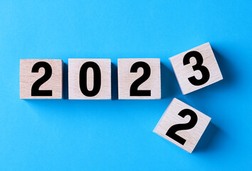 2023 Happy New Year. Wooden cube block change from 2022 to 2023 on blue. Concept 2023 New Year background. Business, resolutions, goals, inspiration, success, ideas