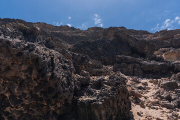 Dark colored rocky desert coastline hiking trail, Fuerteventura, West coast, Spain