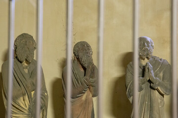 Statues of monks behind cell bars