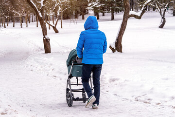 men carries a child in a wheelchair in the winter Park

