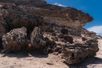 Fototapeta na wymiar Dark rocky desert hiking trail coastline with many small and big stones with holes, Fuerteventura, Canary Islands