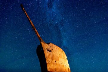 night scene with stars, milky way and a ship wreck