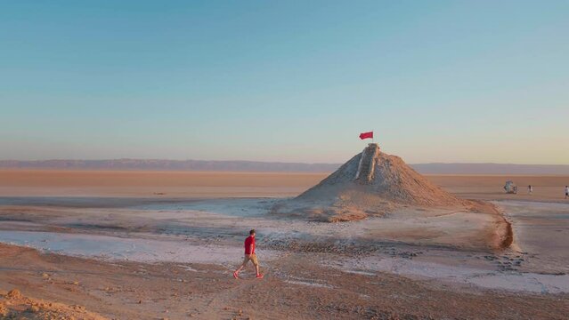Man climbing the sightseeing point of dried salted lake in sahara. Tourist wanting to see the deserted Chott el Djerid lake from peak point.
