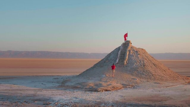 Large view of man climbing the sightseeing point of dried salted lake in sahara. Tourist wanting to see the deserted Chott el Djerid lake from peak point.