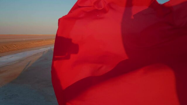 View of red flag fluttering from the peak point Chott el Djerid lake almost dried due to weather contition in desert. Tourists sightseeing of dried lake in sahara desert.