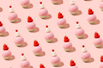 Christmas baubles with warm woolen hats in cupcake molds, creative winter holidays inspired pattern on a candy pink background. 