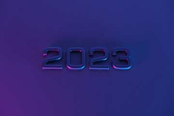 The numbers 2023 in neon light. New Year 2023 on a blue pink background. The postcard is in purple. Merry Christmas.