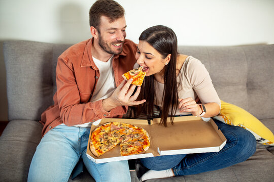 Happy couple eating pizza in apartment