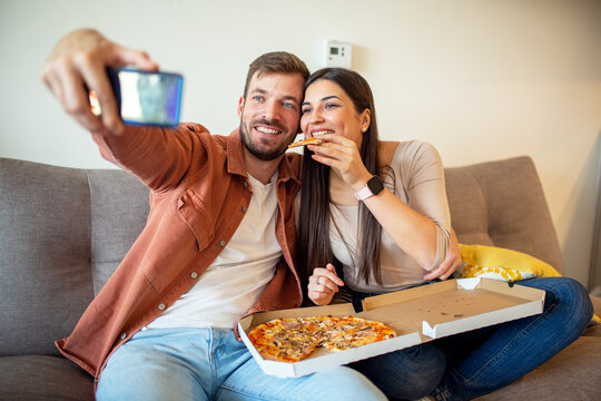 Happy couple eating pizza in apartment