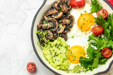Closeup of tasty fried eggs with avocado and mushrooms. Ketogenic diet. Low carb high fat breakfast. Healthy food concept. place for text, top view.