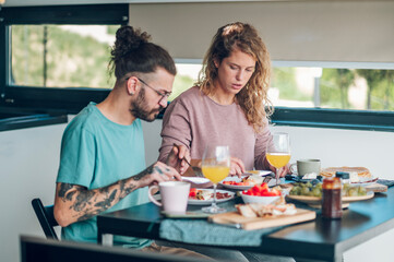 Couple eating breakfast together while sitting at table at home