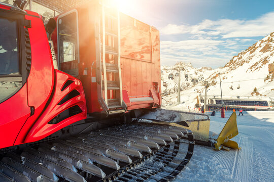 Red modern snowcat ratrack with snowplow snow grooming machine preparing ski slope piste hill at alpine skiing winter resort Ischgl in Austria. Heavy machinery mountain equipment track vehicle