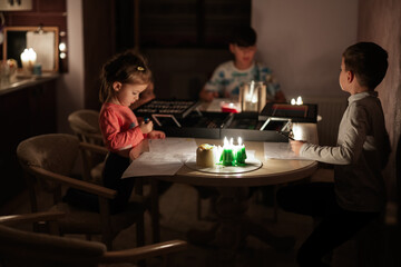 Family spending time together during an energy crisis in Europe causing blackouts. Kids drawing in blackout.