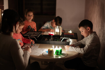 Family spending time together during an energy crisis in Europe causing blackouts. Kids drawing in...