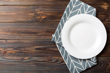 Top view on colored background empty round white plate on tablecloth for food. Empty dish on napkin with space for your design
