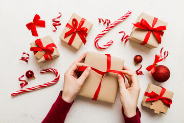 Woman is packing surprise gift for Christmas holidays, sitting at workplace with craft tools, top...