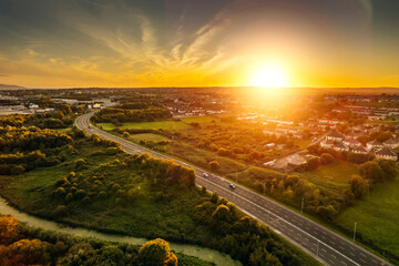 Road in town by a green park and residential area with homes at warm sunset. Sunset time. Stunning...