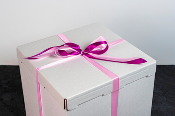 white cardboard gift box tied with a red ribbon on a dark background
