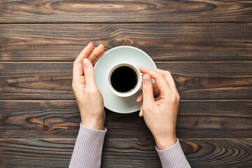 Fototapeta na wymiar Minimalistic style woman hand holding a cup of coffee on Colored background. Flat lay, top view espresso cup. Empty place for text, copy space. Coffee addiction. Top view, flat lay