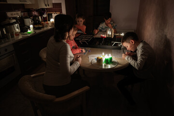 Family spending time together during an energy crisis in Europe causing blackouts. Kids drawing in...