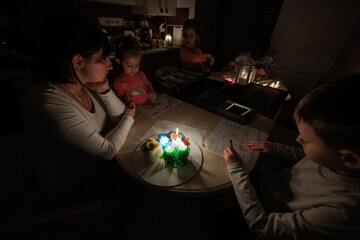 Family spending time together during an energy crisis in Europe causing blackouts. Kids drawing in blackout.