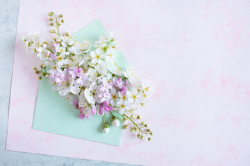 Obraz na płótnie Canvas Bouquet of spring white fruit flowers, bird cherry, lilac in an envelope on decorative watercolor paper. Greeting card for spring holidays, copy space