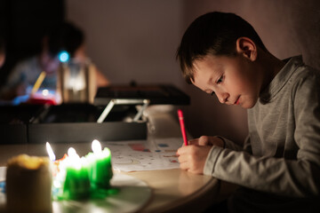 Family spending time together during an energy crisis in Europe causing blackouts. Kids drawing in blackout.