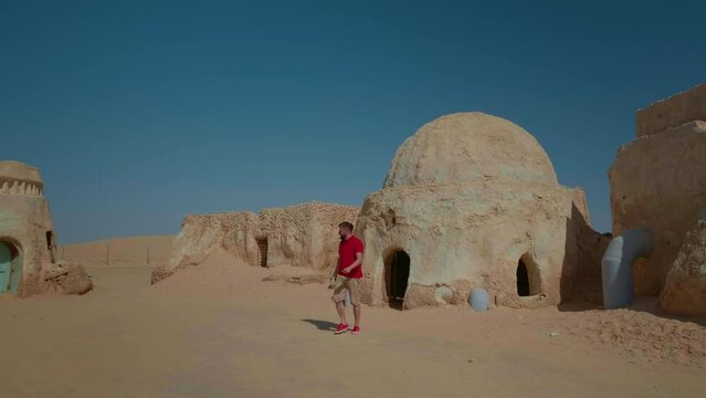 Large shot of man on Star Wars filming stage in Tunisian desert. Traveller exiting a filming decoration shelter.