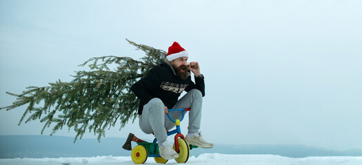 Crazy winter man on bicycle caring christmas tree. Man with snowman on winter outdoor background....