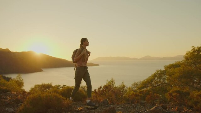 Young woman hiking in mountains at sunset. Tourist traveler with backpack on hike