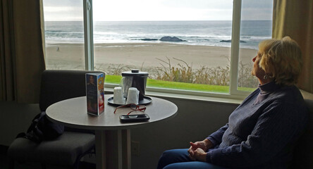 Reflection at the Beach - a woman in motel room enjoying the surf and ocean