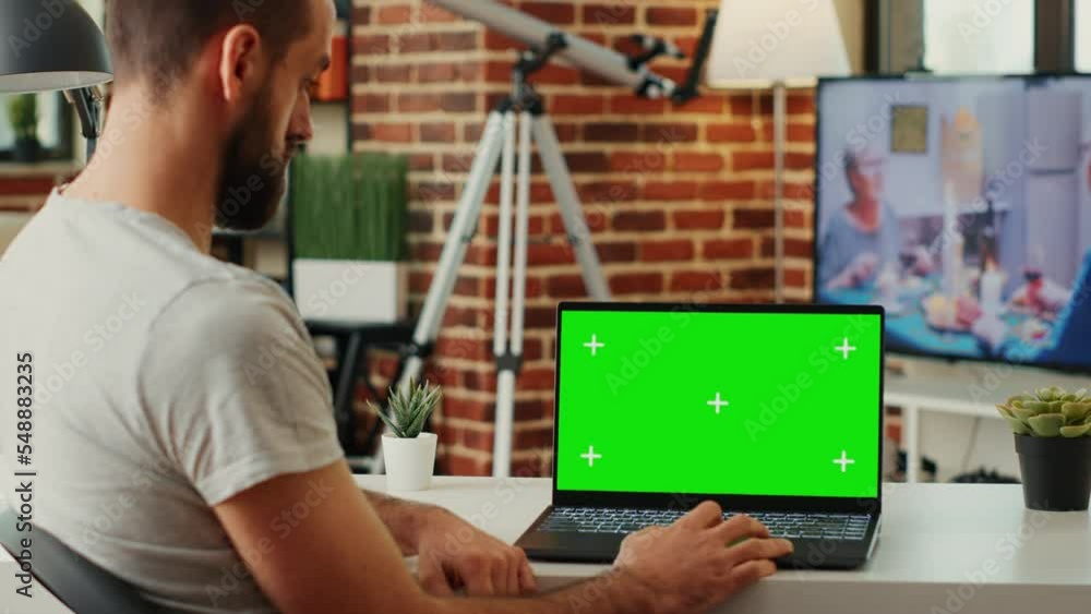 Poster modern manager looking at laptop with greenscreen display and analyzing blank chroma key template on